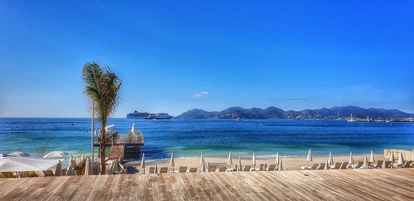 Scenic view of swimming pool by sea against blue sky