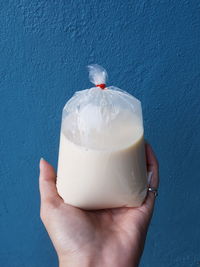 Cropped image of hand holding ice cream against wall