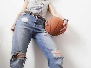 Midsection of woman with basketball against white background