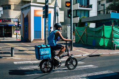 Rear view of man riding bicycle on road