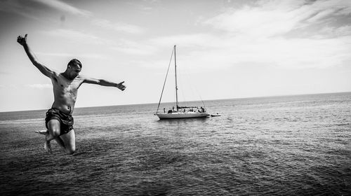 Man diving into sea with boat in background