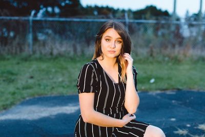 Fashionable teenage girl sitting outdoors