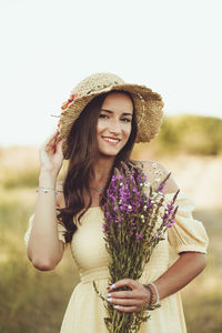 Portrait of young woman wearing hat standing on land