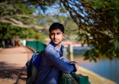 Portrait of young man standing against trees