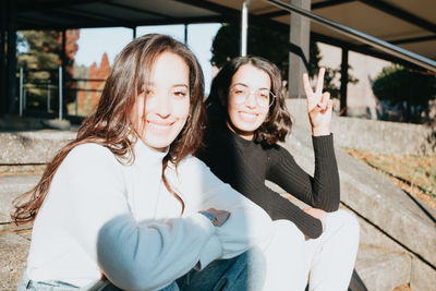 Portrait of smiling sisters sitting on steps