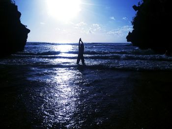 Silhouette man standing on beach against sky during sunset