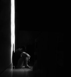 Side view of depressed man sitting in darkroom