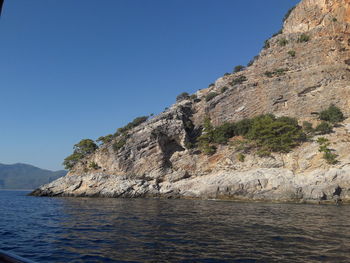 Scenic view of sea and mountains against clear blue sky