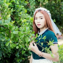 Portrait of beautiful young woman standing against plants