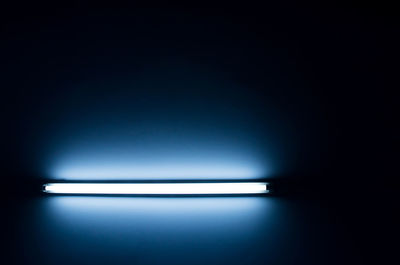 Close-up of illuminated light bulb against wall in darkroom