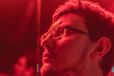 Man wearing eyeglasses while looking away with red light 