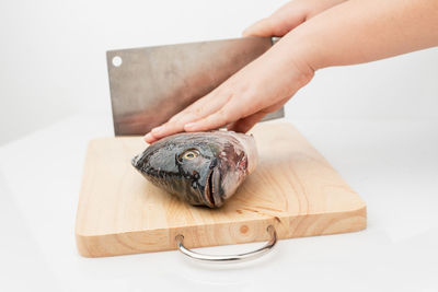 Person holding fish on cutting board