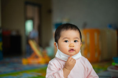 Portrait of cute baby girl wearing mask at home