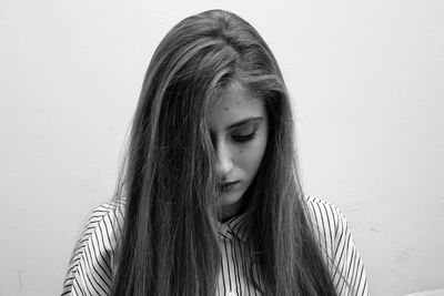 Beautiful young sad woman looking down against gray background