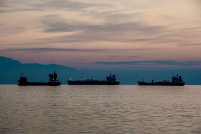 Boats in sea at sunset