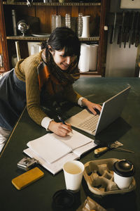 Smiling female entrepreneur working on laptop in upcycling store