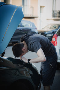 A young man takes out a car headlight bulb.