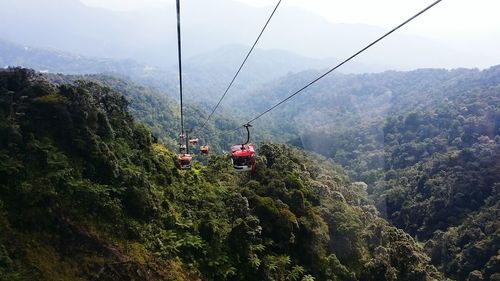 Overhead cable cars over green mountains