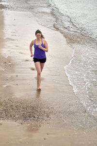 High angle view of woman jogging on shore at beach