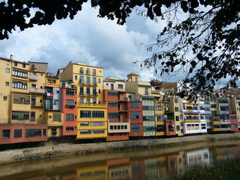 Buildings by river against sky