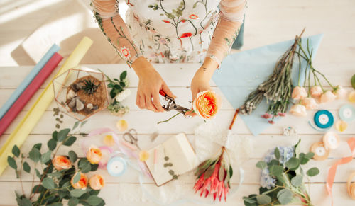 High angle view of woman holding flowers on table