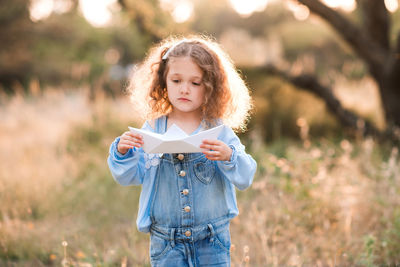 Girl holding paper boat at park