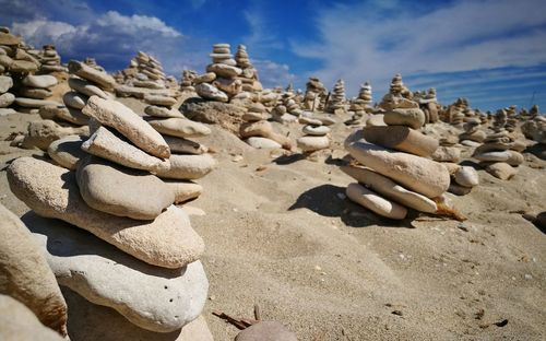 Stack of stones on sand at beach against sky