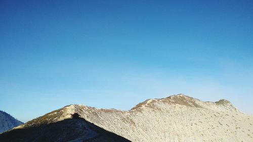 Low angle view of mountains against clear blue sky