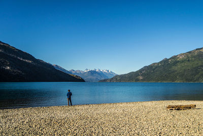 Scenic view of sea and mountains against clear blue sky