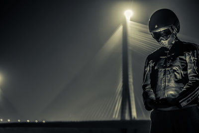 Man standing by bridge at night