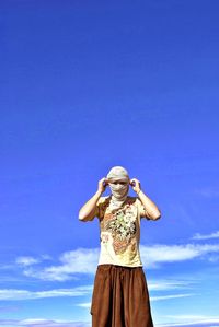 Low section of woman standing against blue sky