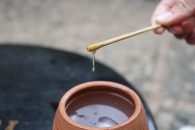 Close-up of hand holding honey on stick over container