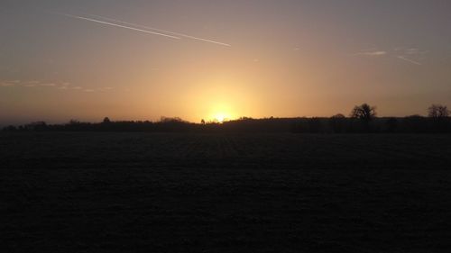 Scenic view of silhouette field against sky at sunset