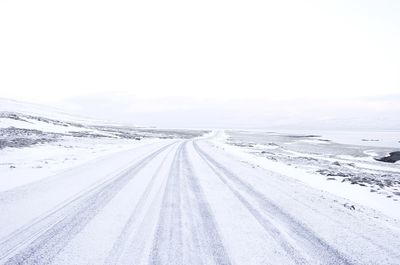 Country road amidst snowcapped landscape against sky