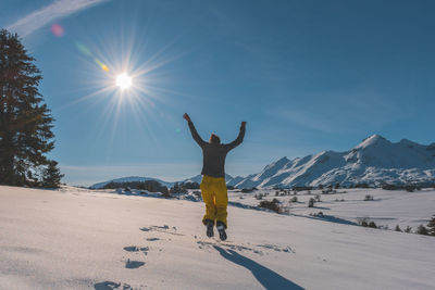 An unrecognizable playful young caucasian woman jumping in the french alps mountains