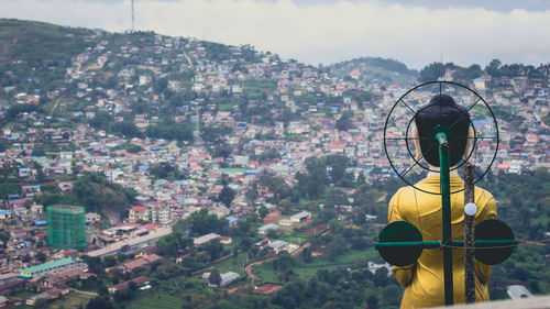 Rear view of woman standing by buildings against sky