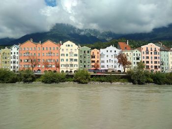 Buildings by river against sky