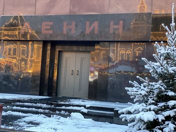 Text on snow covered house against building