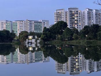 Reflection of buildings in lake against clear sky