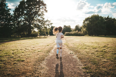 Rear view of girl running on field