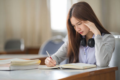 Young woman reading book on table