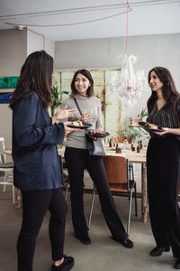 Full length of multi-ethnic female colleagues enjoying lunch while standing at workshop