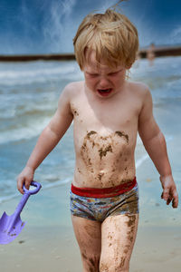 Full length of shirtless boy on beach