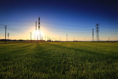 Electricity pylon on field against sky during sunset