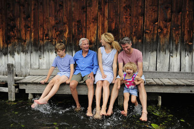 Family sitting together on jetty splashing with water