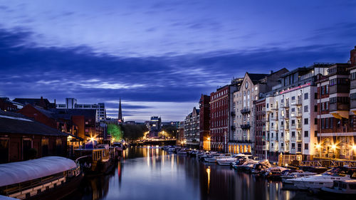 Boats moored in illuminated city against sky at night