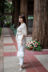 Full length of woman standing by potted plant