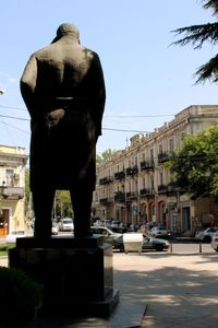 Statue in city against sky