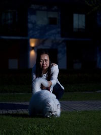 Woman with dog crouching on footpath at night