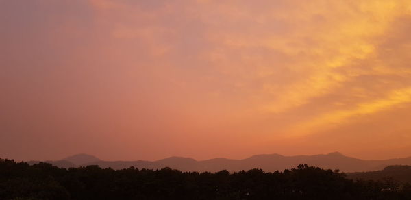 Scenic view of silhouette mountains against orange sky